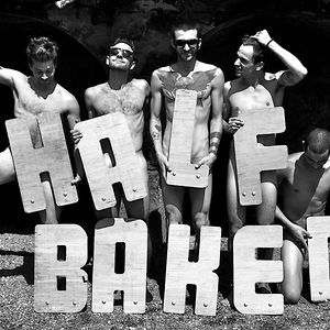 Five shirtless men stand behind large wooden letters spelling 'HAVE BAKE' in a black and white photo.